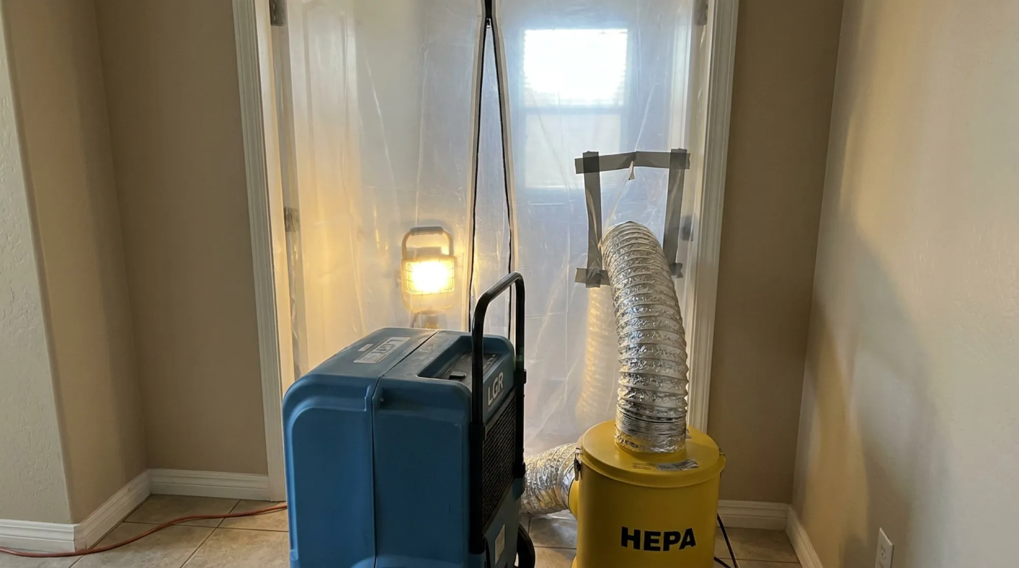 A sealed containment barrier with a zippered entry and negative air machine set up in a Phoenix hallway before mold removal begins.